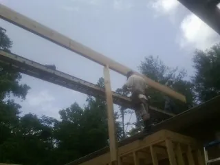 Carpenter setting a ridge beam over a new addition frame — Ice Dam Removal by Roofing Brothers in Council