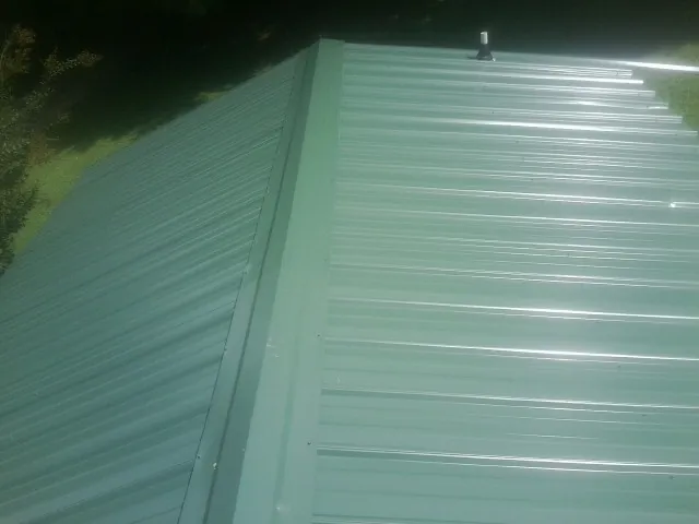 New green metal panels meeting at the ridge of a roof — Flat Roof Repair work by our crew in Council