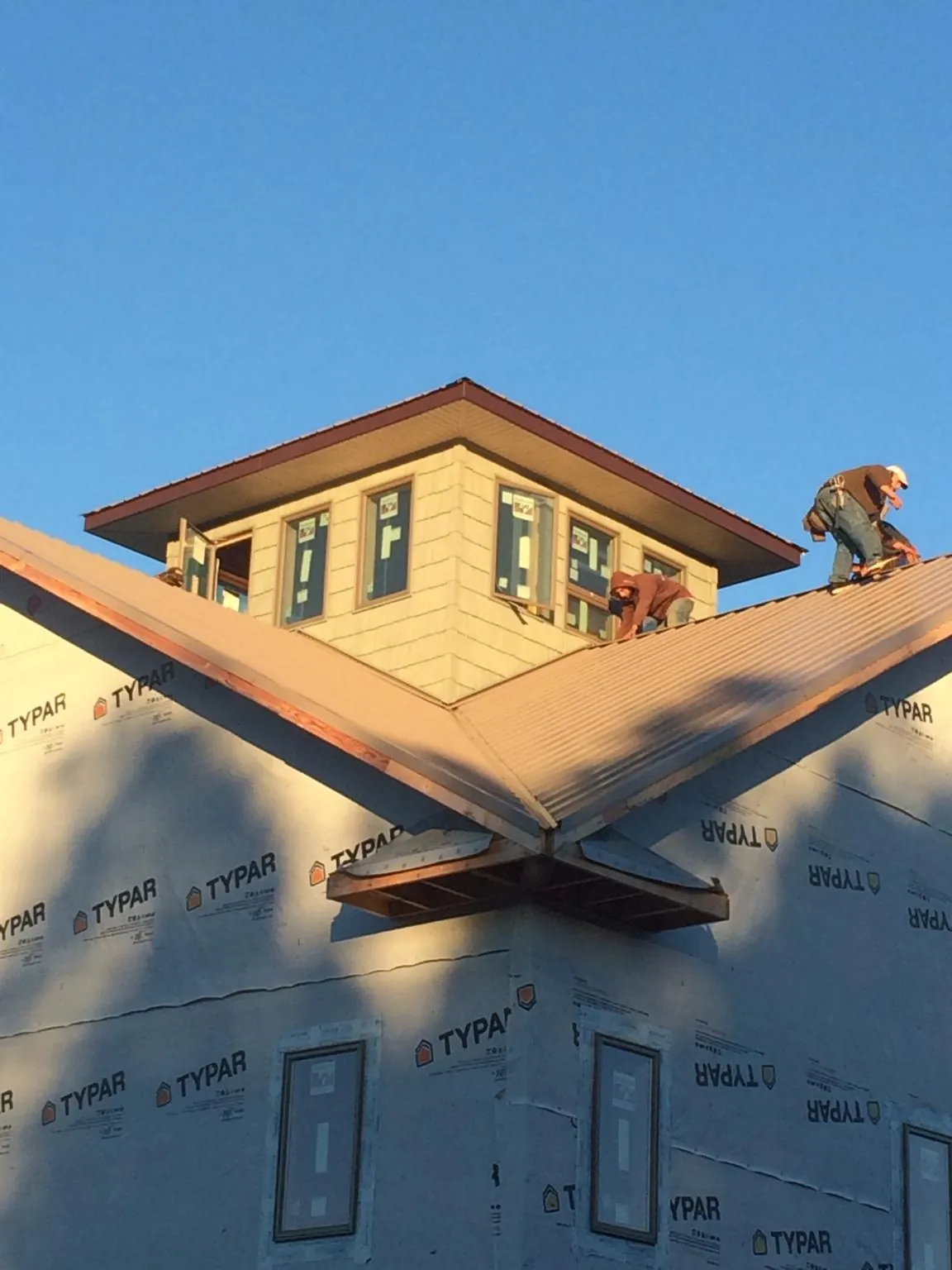 Roofers working around a rooftop cupola on a new metal roof at sunset — Roof Waterproofing in Council by Roofing Brothers